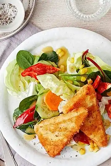 Knuspriger gebackener Feta auf buntem Gemüsesalat mit Honig-Dressing